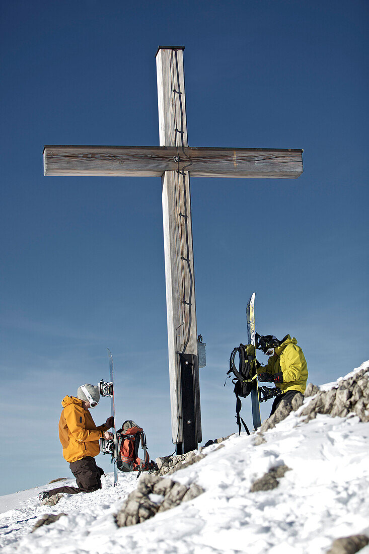 Two snowboarders near summit cross, Oberjoch, Bad Hindelang, Bavaria, Germany