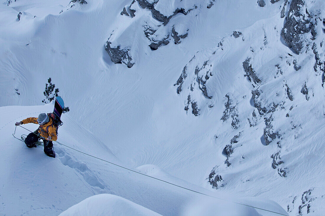 Snowboarder holding climbing rope, Oberjoch, Bad Hindelang, Bavaria, Germany