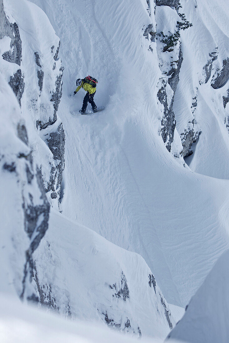 Snowboarder riding in the deep snow between rocks aside the slope, Oberjoch, Bavaria, Germany