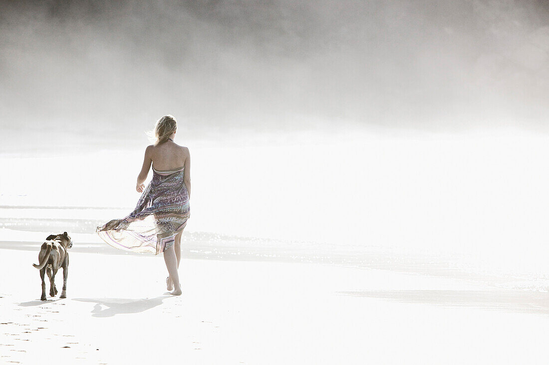 Young woman walking at the beach with a dog, Fuerteventura, Spain