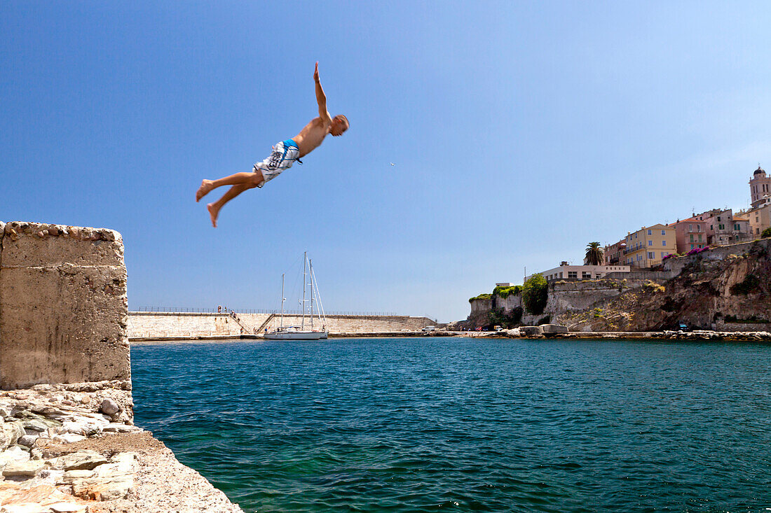Kid dives into the water, old harbor, Bastia, Corsica, France