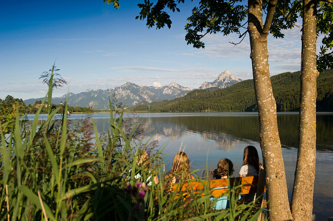 Children looking over lake Weissensee to mountain scenery, Fuessen, Allgaeu, Bavaria, Germany