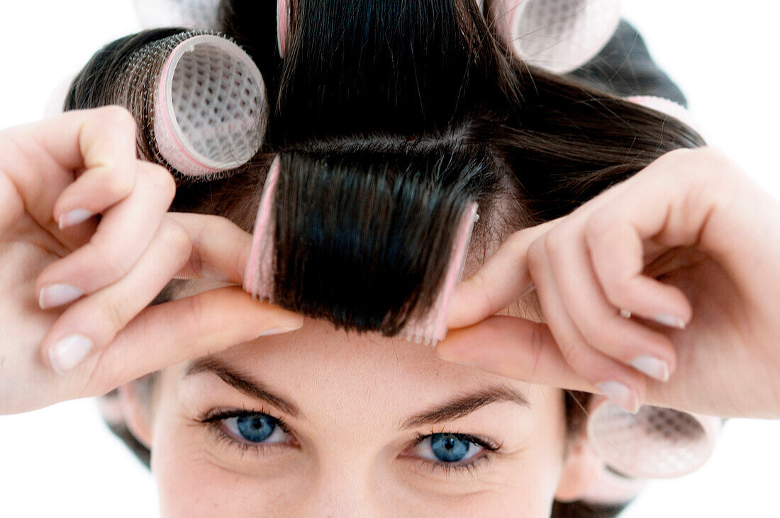 Portrait of a young woman in curlers, close up (studio)