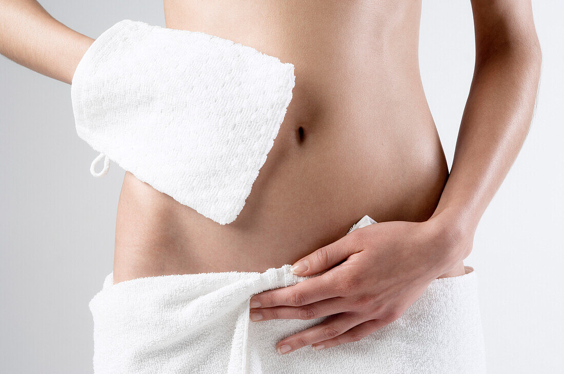 Naked woman, hand on towel on her sex, washcloth, close up (studio)