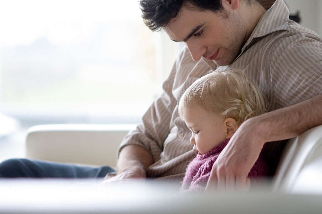 Man with little boy sitting on a sofa, side view