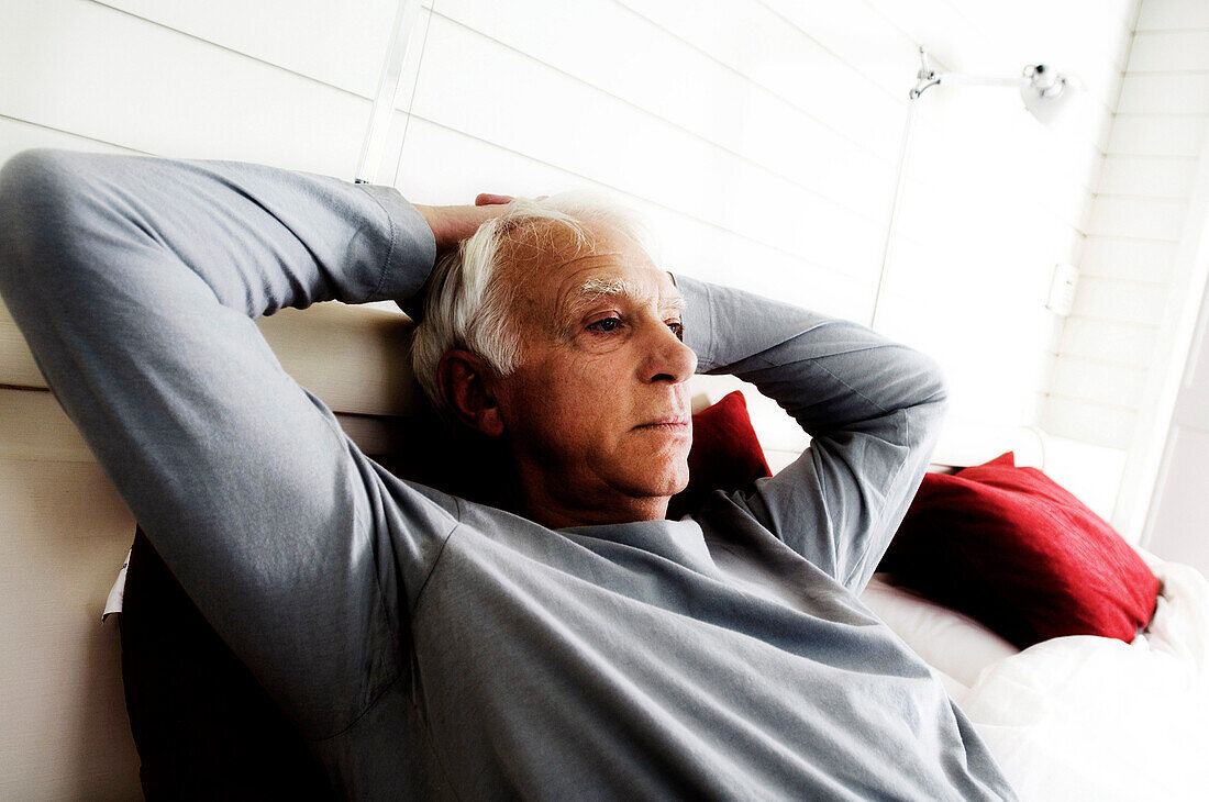 Senior man relaxing, lying on a bed