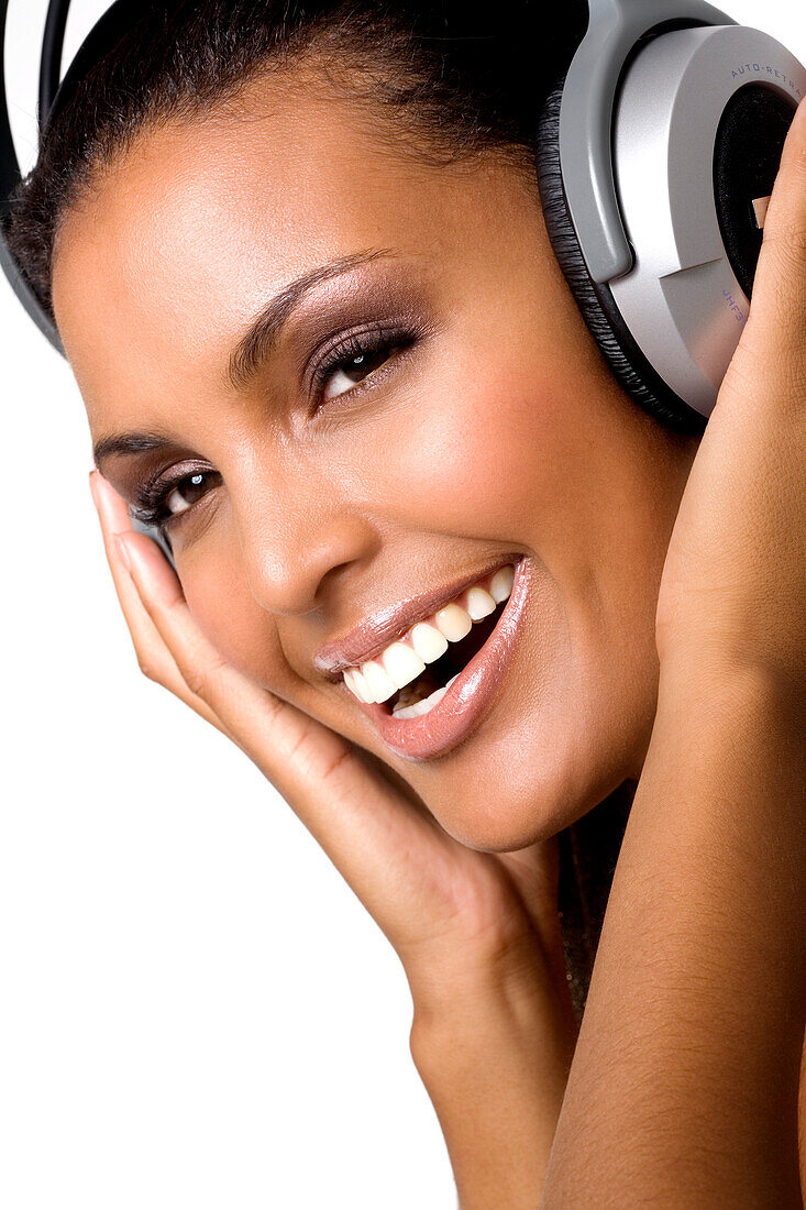 Portrait of a young smiling woman, listening to music with headphones