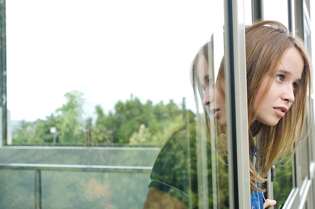Thinking teenage girl at window