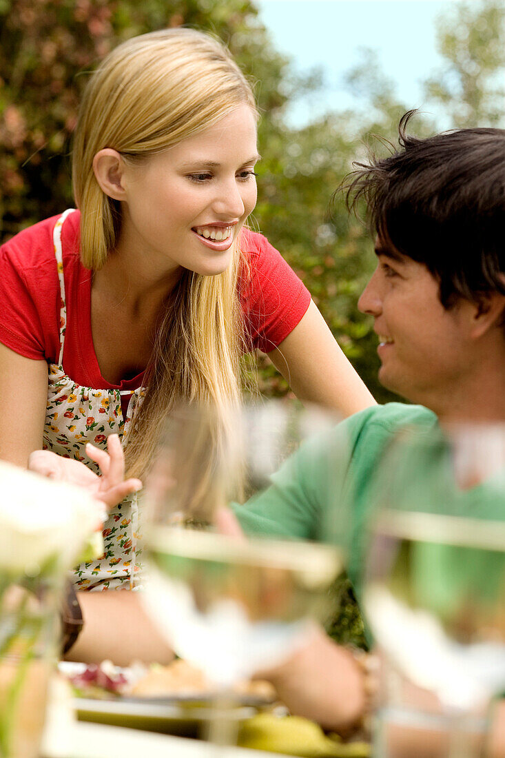 Young couple talking at garden table, outdoors