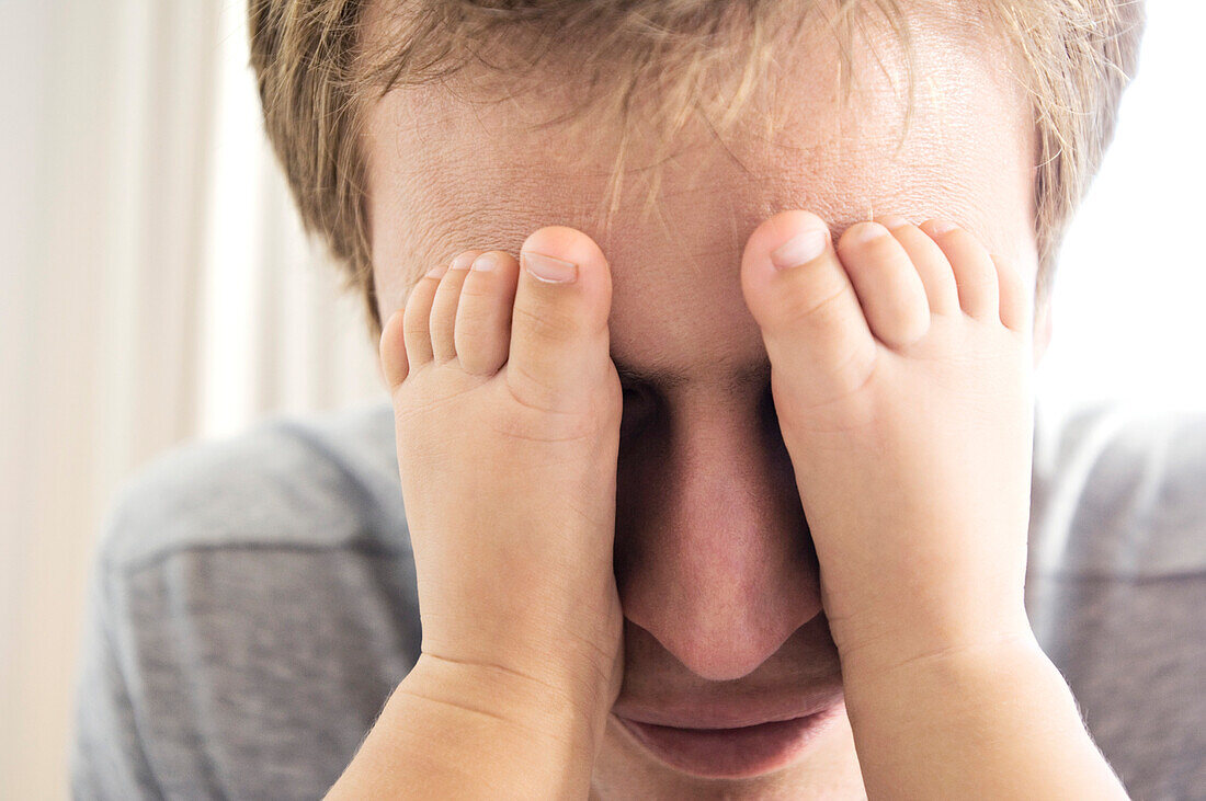 Father playing with his baby, feet on his eyes, indoors