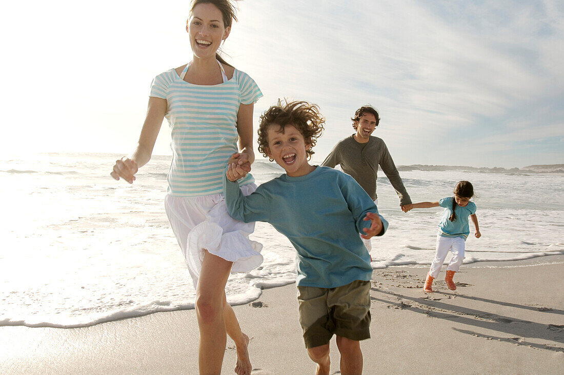 Parents and two children walking on the beach, outdoors