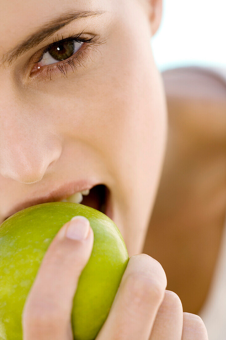 Portrait of a young woman eating an apple, indoors