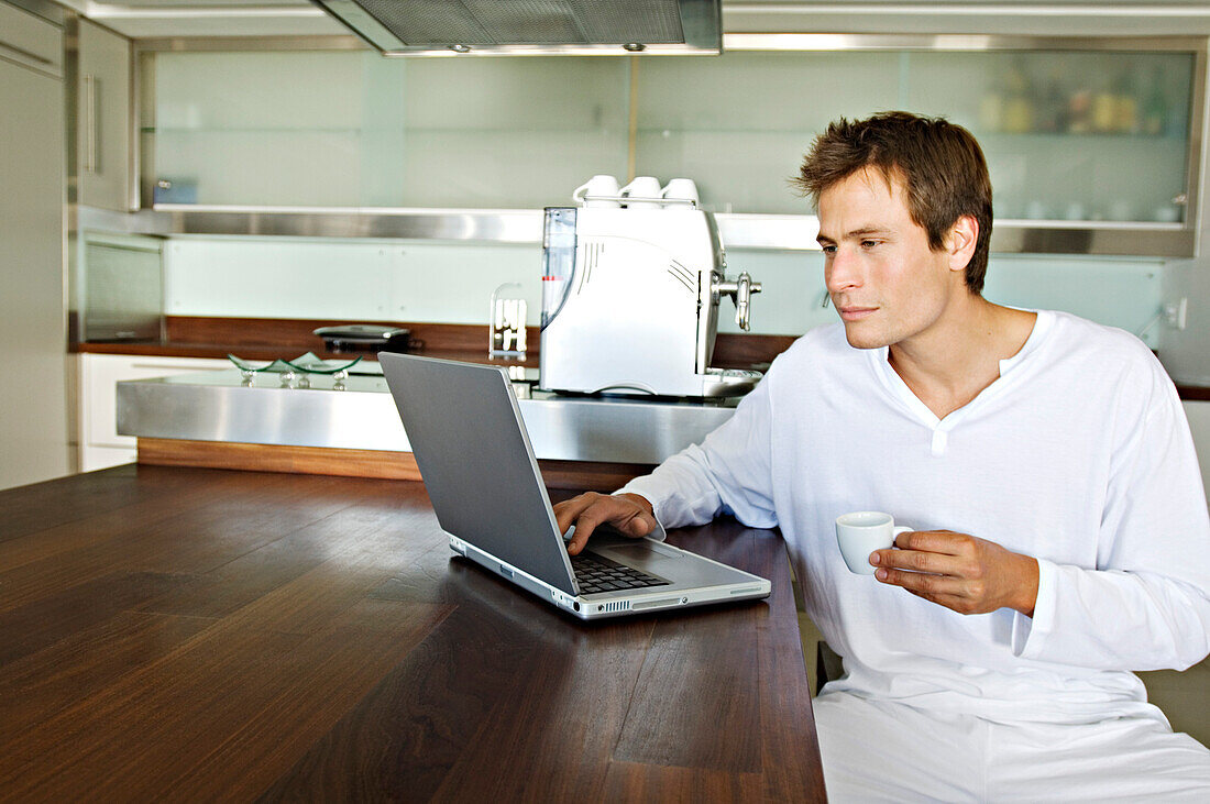 Young man using laptop in kitchen