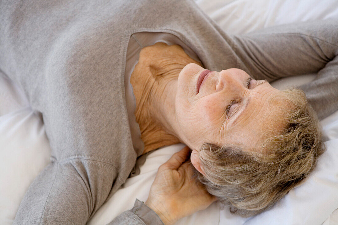 Senior woman sleeping, hands behind head