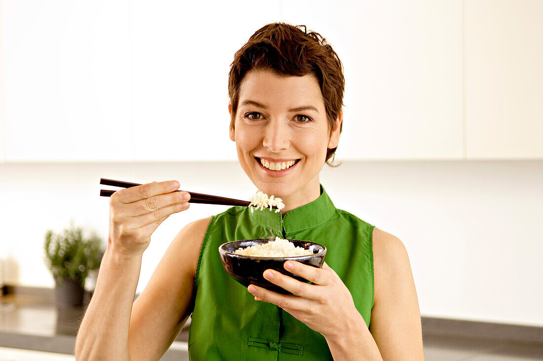 Portrait of a mid adult woman eating rice with chopsticks