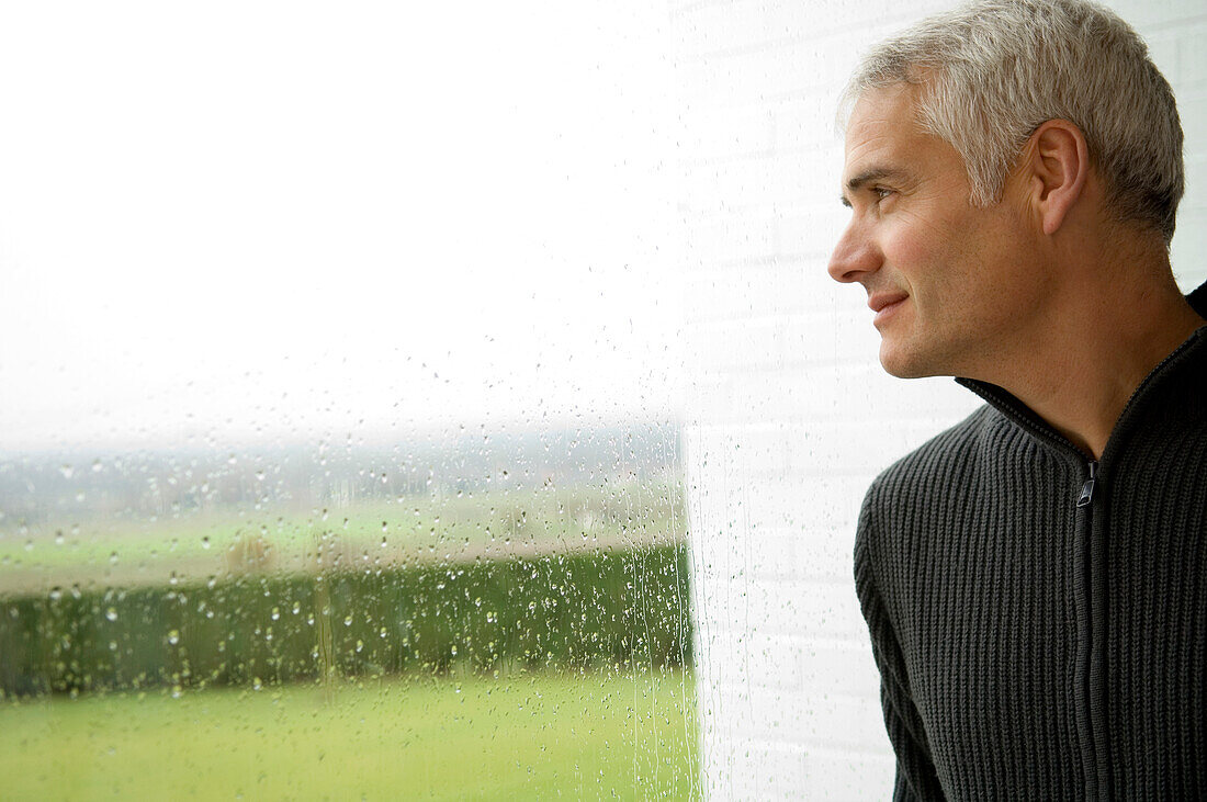 Close-up of a mature man looking out through a window