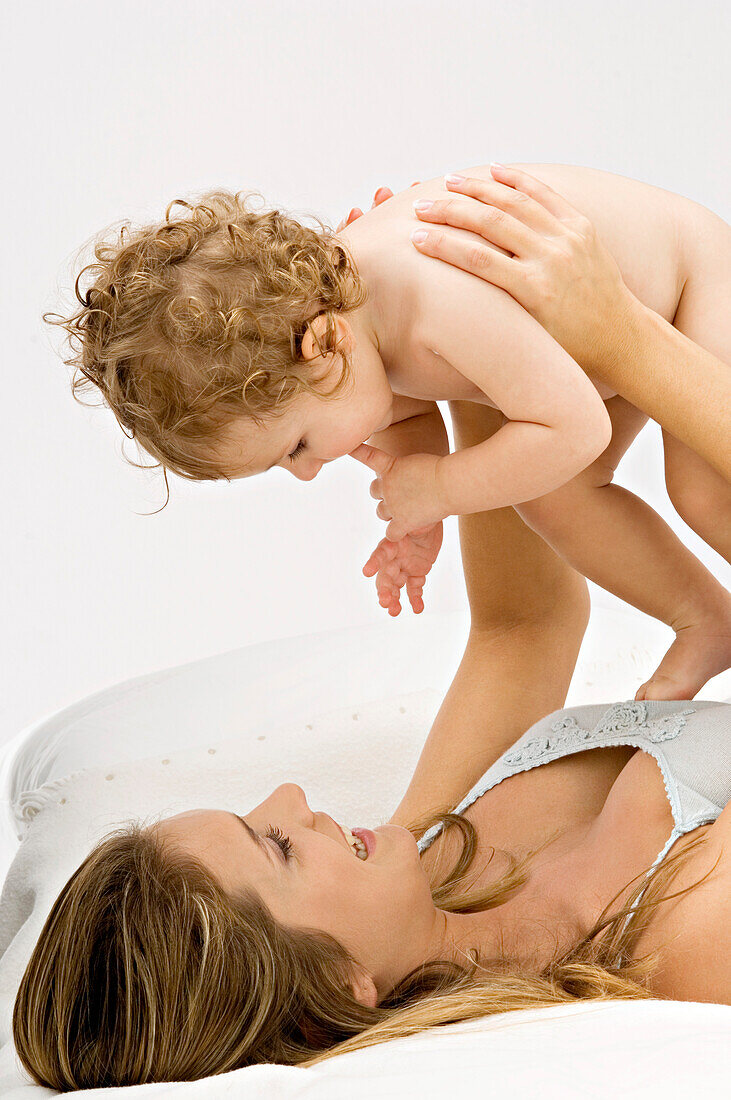 Close-up of a young woman lying and playing with her son