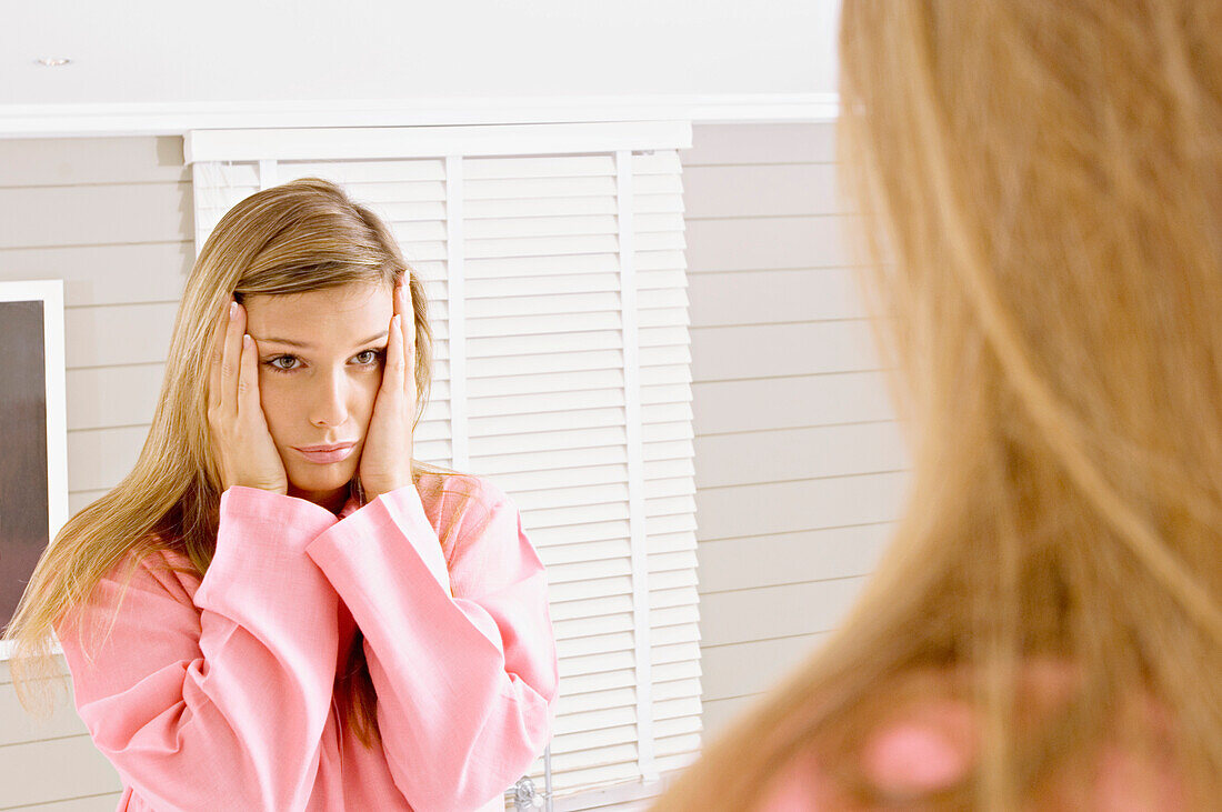 Reflection of a young woman in a mirror looking sad