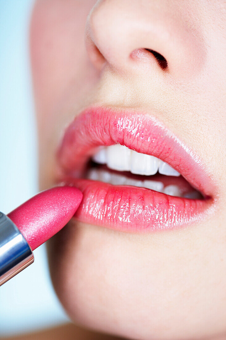 Young woman applying lipstick, close-up