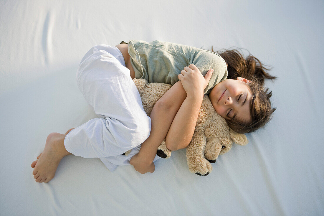 High angle view of a girl sleeping with a teddy bear