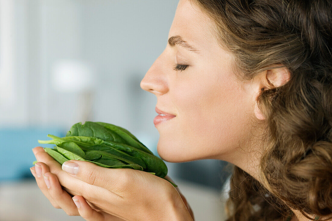 Woman smelling spinach leaves in the kitchen