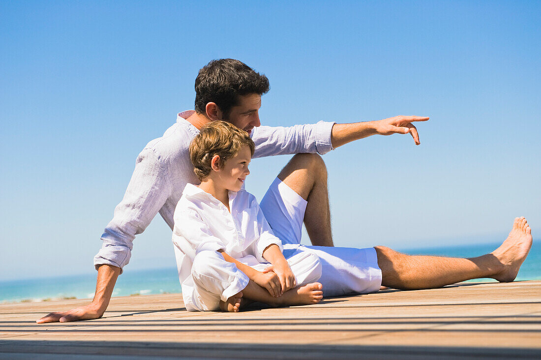 Man sitting on a boardwalk with his son