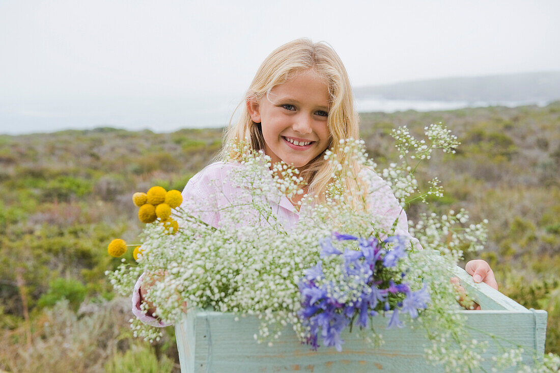 Girl carrying a box of flowers and smiling