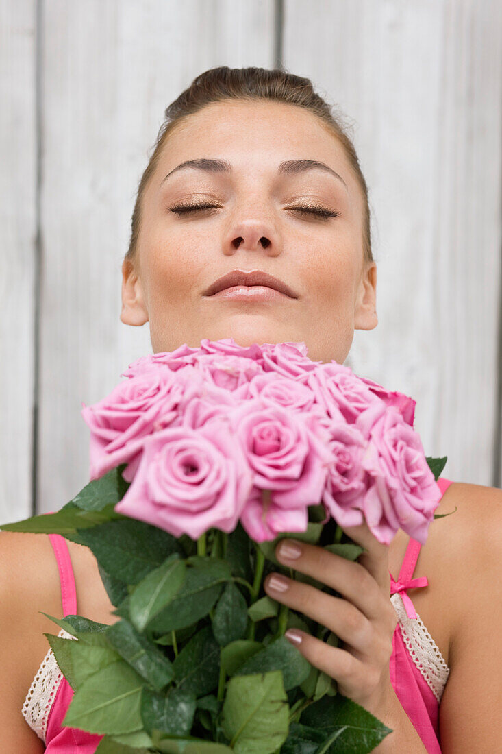 Woman smelling pink roses – License image – 70370613 lookphotos