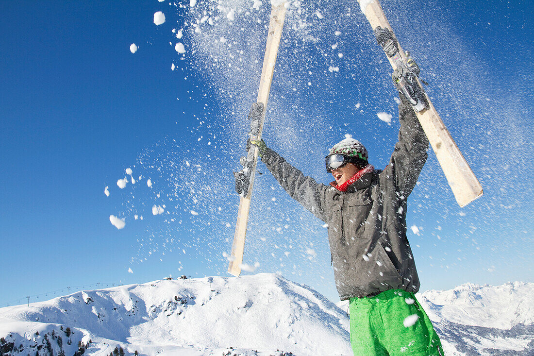 Young man holding his skis above his head