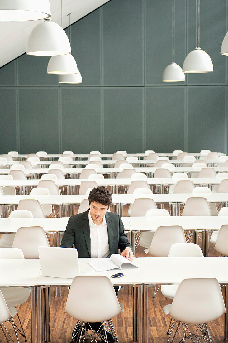 Businessman sitting at a cafeteria and using a laptop