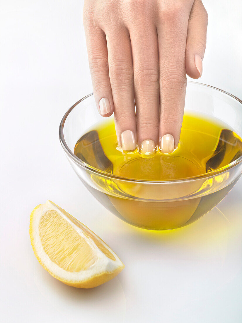 Nahaufnahme einer Frauenhand in einer Schale mit Olivenöl