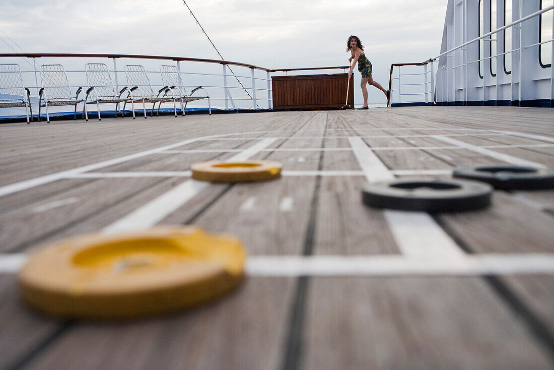 Frau spielt Shuffleboard an Deck von Kreuzfahrtschiff MS Astor, Transocean Kreuzfahrten, nahe Kiel, Schleswig-Holstein, Deutschland, Europa