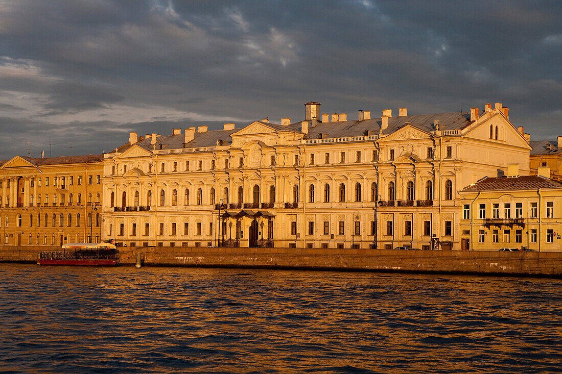 Golden-lit house facades along banks of Neva river, St. Petersburg, Russia