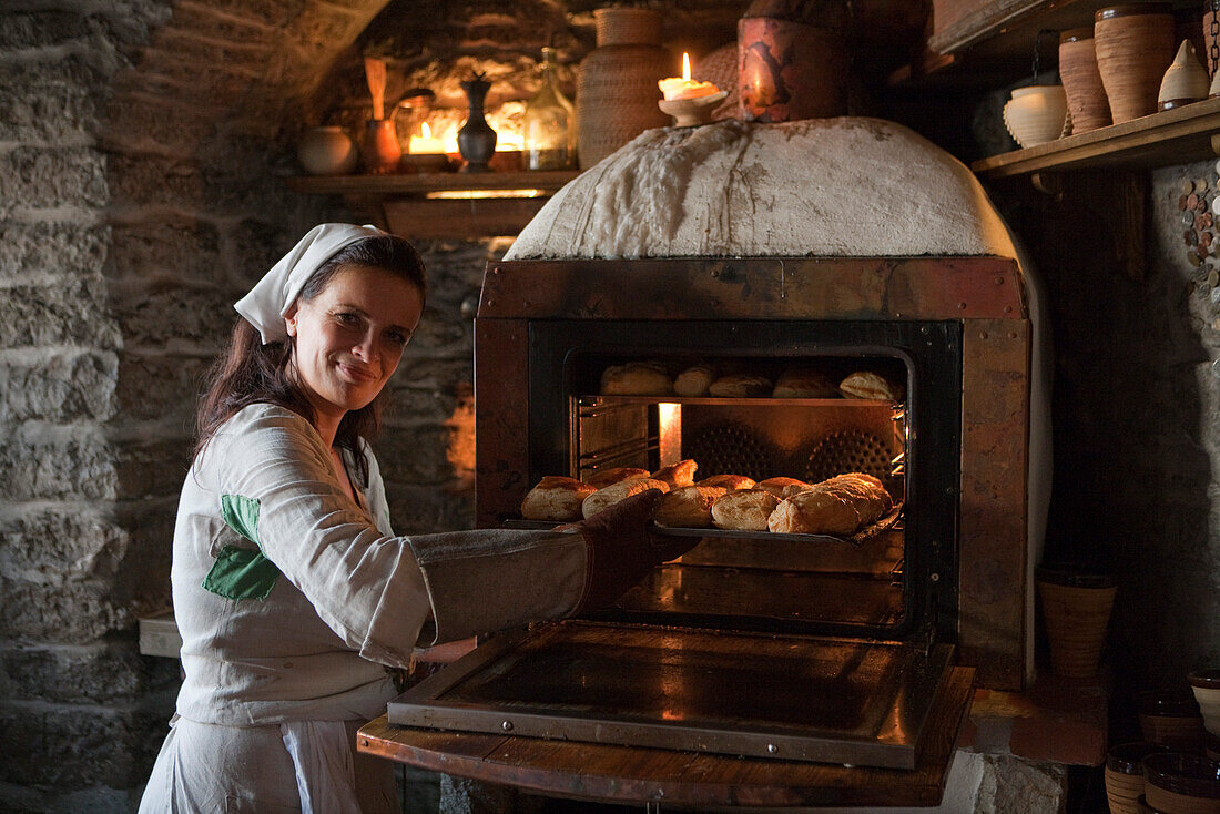 Woman in medieval costume bakes bread rolls and pies at Inn Krug Korts restaurant at Town Hall Square (Raekoja Plats), Tallinn, Harjumaa, Estonia