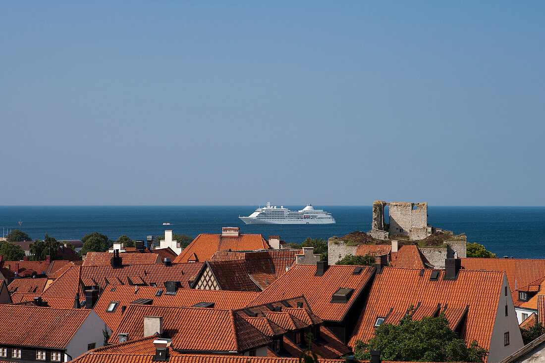 Blick über die Dächer von Visby mit Kreuzfahrtschiff Silver Whisper (Silversea Cruises) auf Reede in der Ostsee, Visby, Gotland, Schweden, Europa