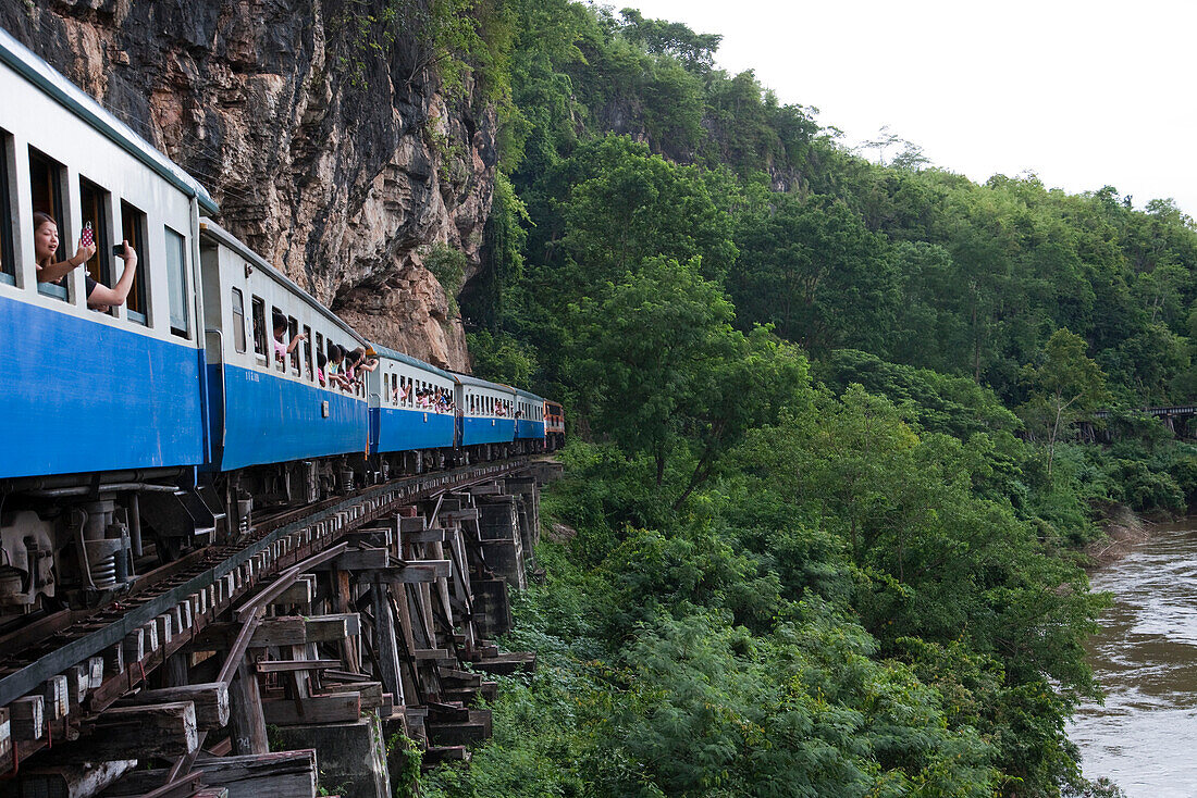 Mit Touristen besetzte Waggons auf hölzernen Viadukt Saphan Tham Krasae der Trans-River Kwai Death Railway Eisenbahn entlang dem Fluss River Kwai Noi, nahe Kanchanaburi, Thailand, Asien