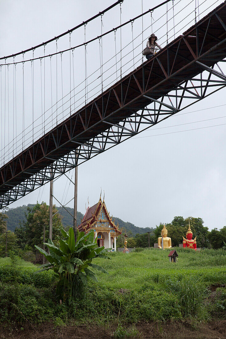 Frau radelt über eine Brücke über dem Fluss River Kwai Noi in der Nähe vom Sai Yok Nationalpark, nahe Kanchanaburi, Thailand, Asien