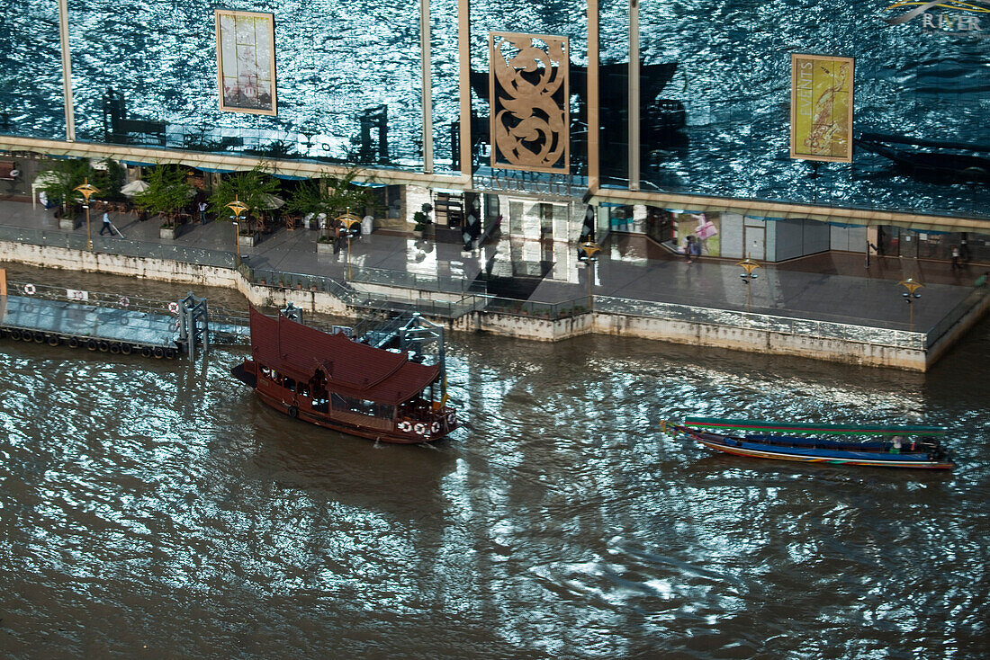 Glass reflection of boats alongside River City on Chao Praya River seen from Millennium Hilton Hotel, Bangkok, Thailand