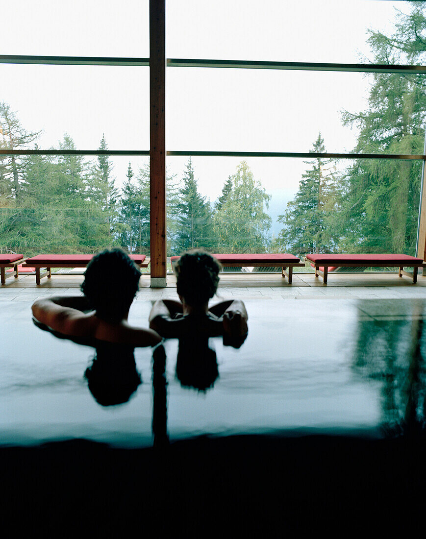 Paar im Innenpool vor Panoramafenster, Vigilius Mountain Resort, Vigiljoch, Lana, Trentino-Südtirol, Italien