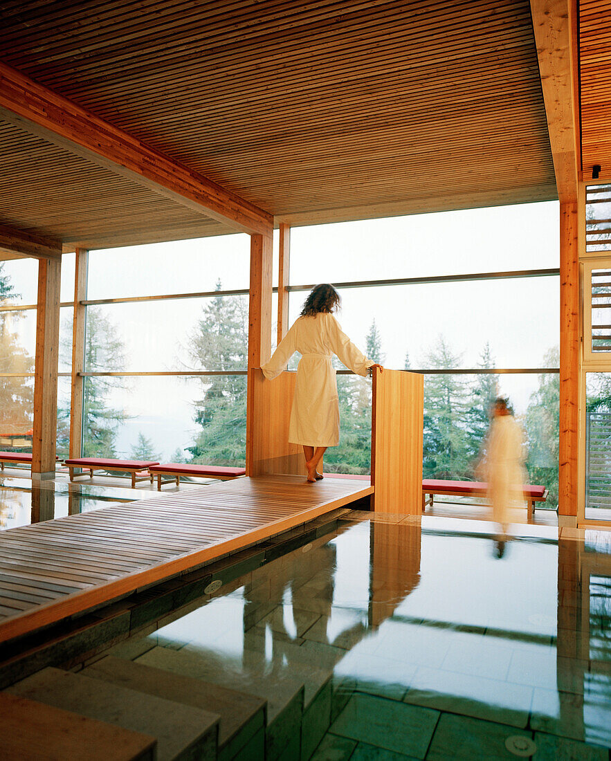 Couple near indoor pool looking out of a panorama window, Vigilius Mountain Resort, Vigiljoch, Lana, Trentino-Alto Adige/Suedtirol, Italy