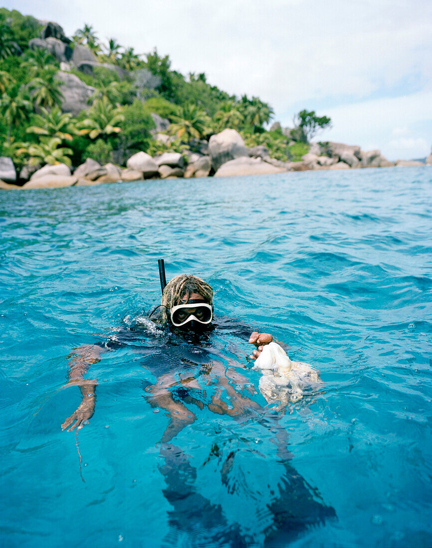 Octopusjäger Alvis Jean schnorchelt vor der Insel Felicité, La Digue and Inner Islands, Republik Seychellen, Indischer Ozean
