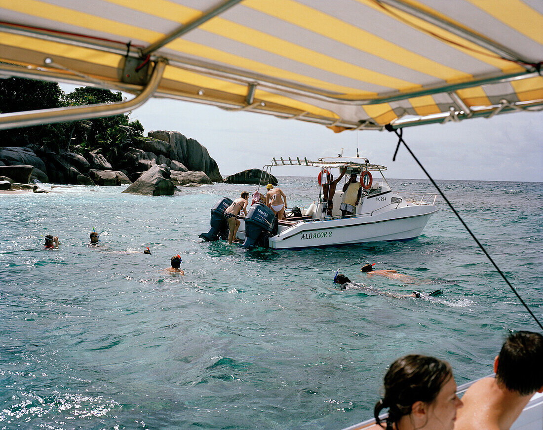 Menschen schnorcheln vor winziger Insel Coco Island, La Digue and Inner Islands, Republik Seychellen, Indischer Ozean