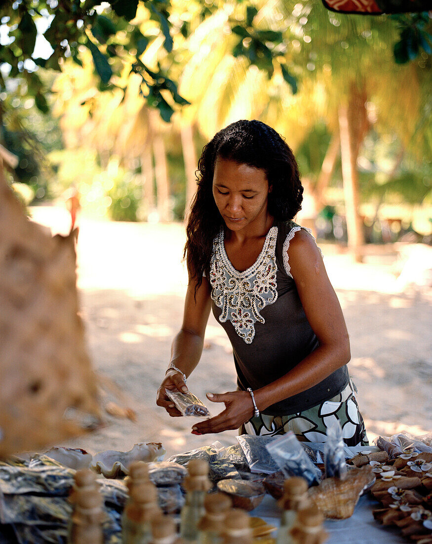 Woman is selling souvenirs and coconuts, south western La Digue, La Digue and Inner Islands, Republic of Seychelles, Indian Ocean