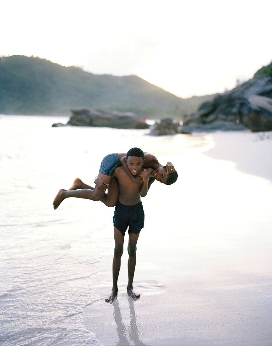 Zwei Jungen am Strand der Bucht Baie Lazare, südwestliches Mahe, Republik Seychellen, Indischer Ozean