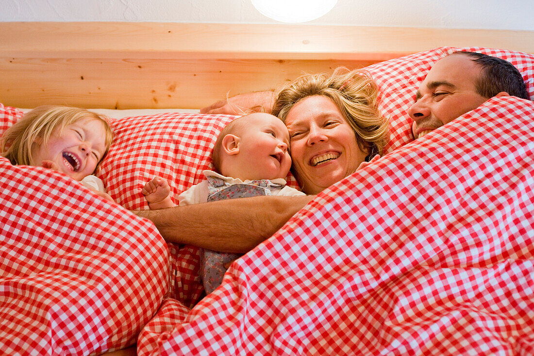 Familie liegt lachend im Bett