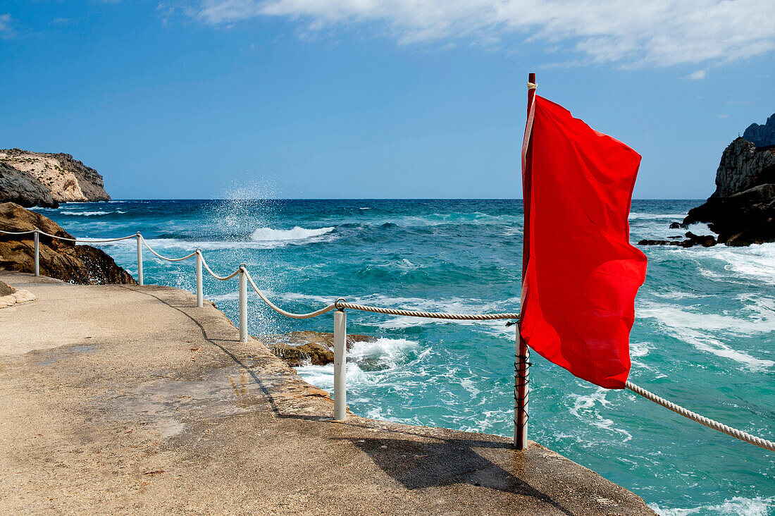 Red flag waving in Cala Sant Vicenc, Mallorca, Balearic Islands, Spain