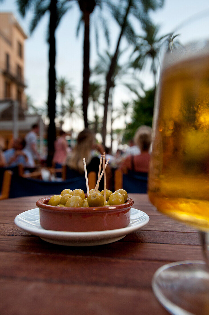 Beer & olives in cafe in palm filled square, Palma, Majorca, Spain
