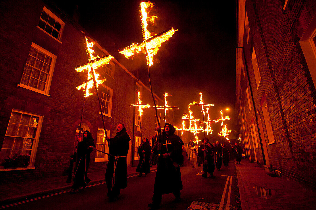 People Dressed As Monks From Southover Bonfire Society Walking In Procession Down Street Carrying Burning Crosses To Commemorate The 17 Protestant Martyrs Burnt At The Stake. Bonfire Night 2009. Lewes, East Sussex, Uk.