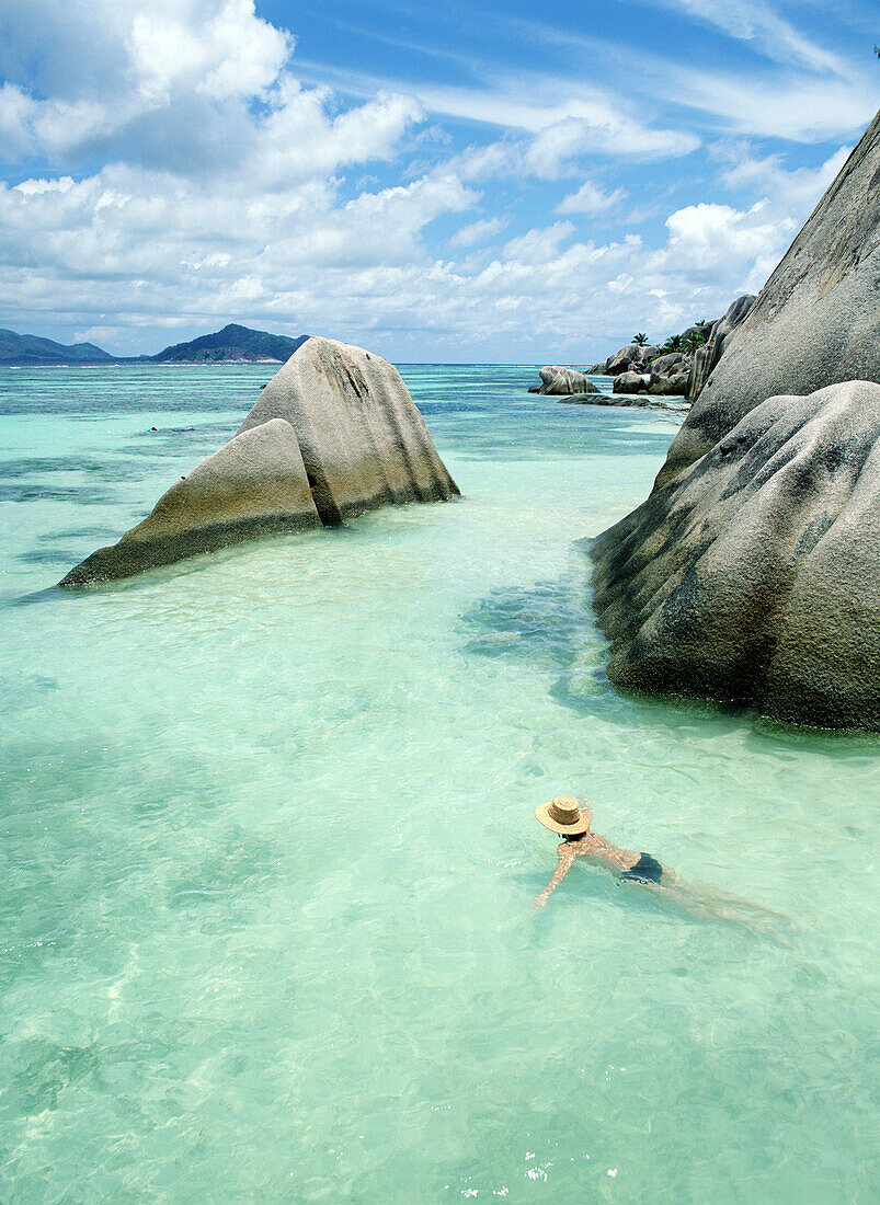 Woman swimming close to shore beside boulders, Anse Source D'Argent, La Digue, The Seychelles