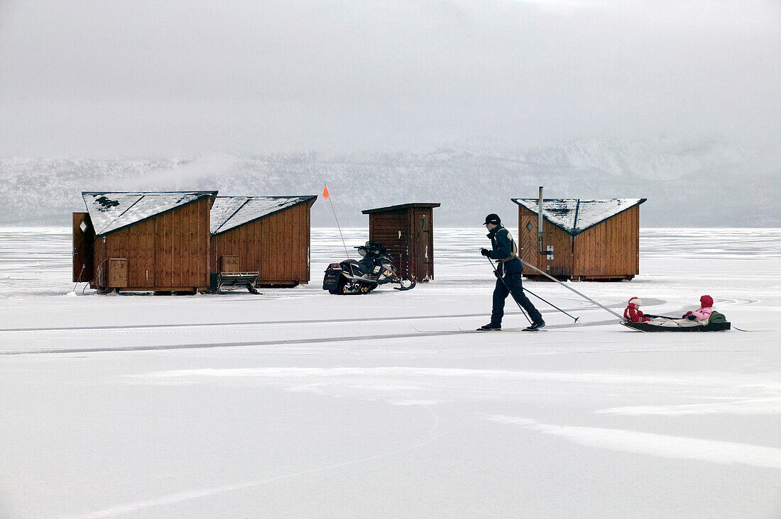 Person pulling child in sled by Abisko Ark Hotel cabins, Abisko, Sweden